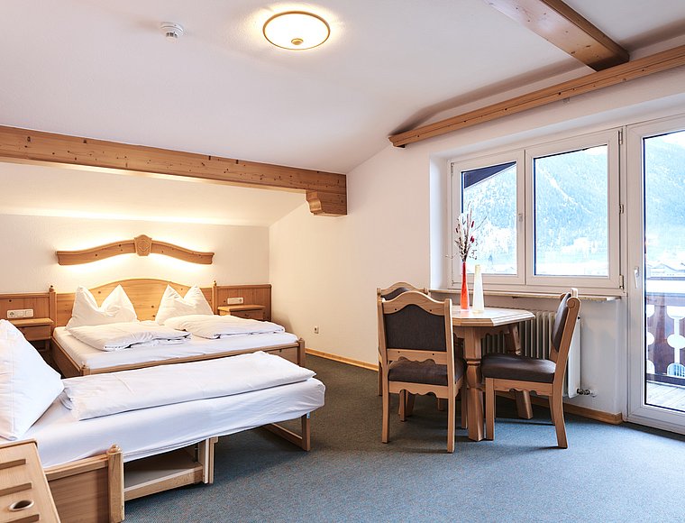 Spacious room with double bed, pull-out bed and seating area near window front