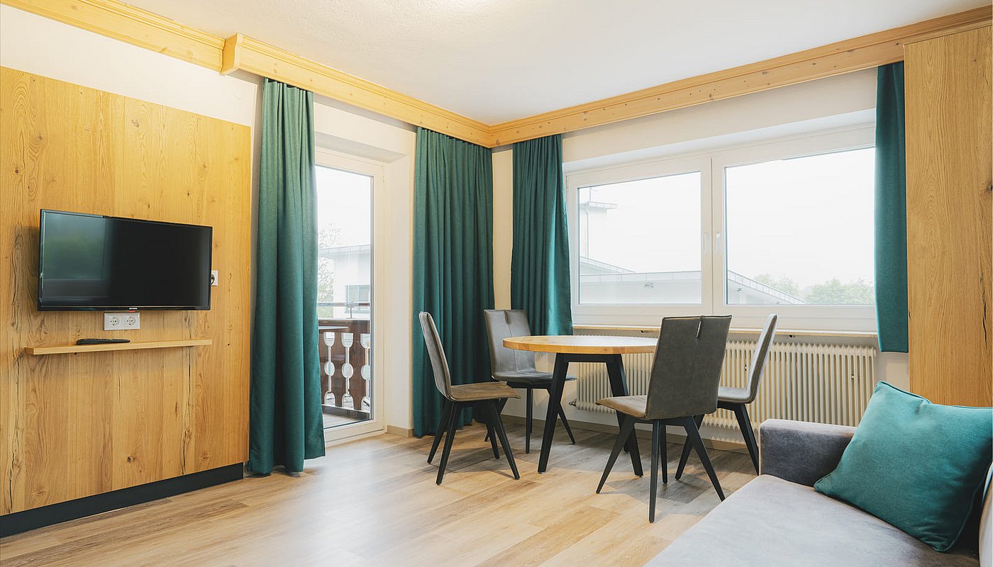 Living room in the holiday apartment with a wooden wall, TV, round table and access to the balcony