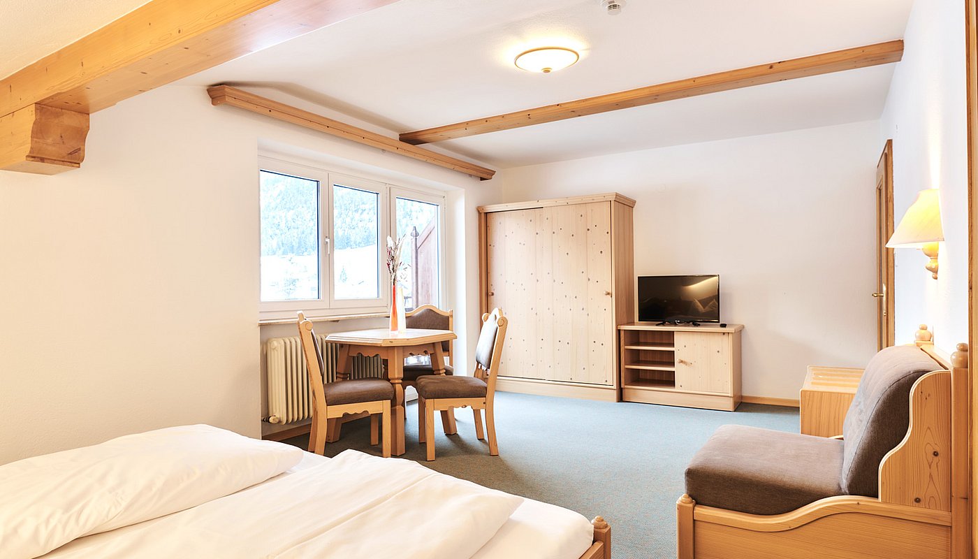 Bright room with double bed, dining table and large window front with mountain view