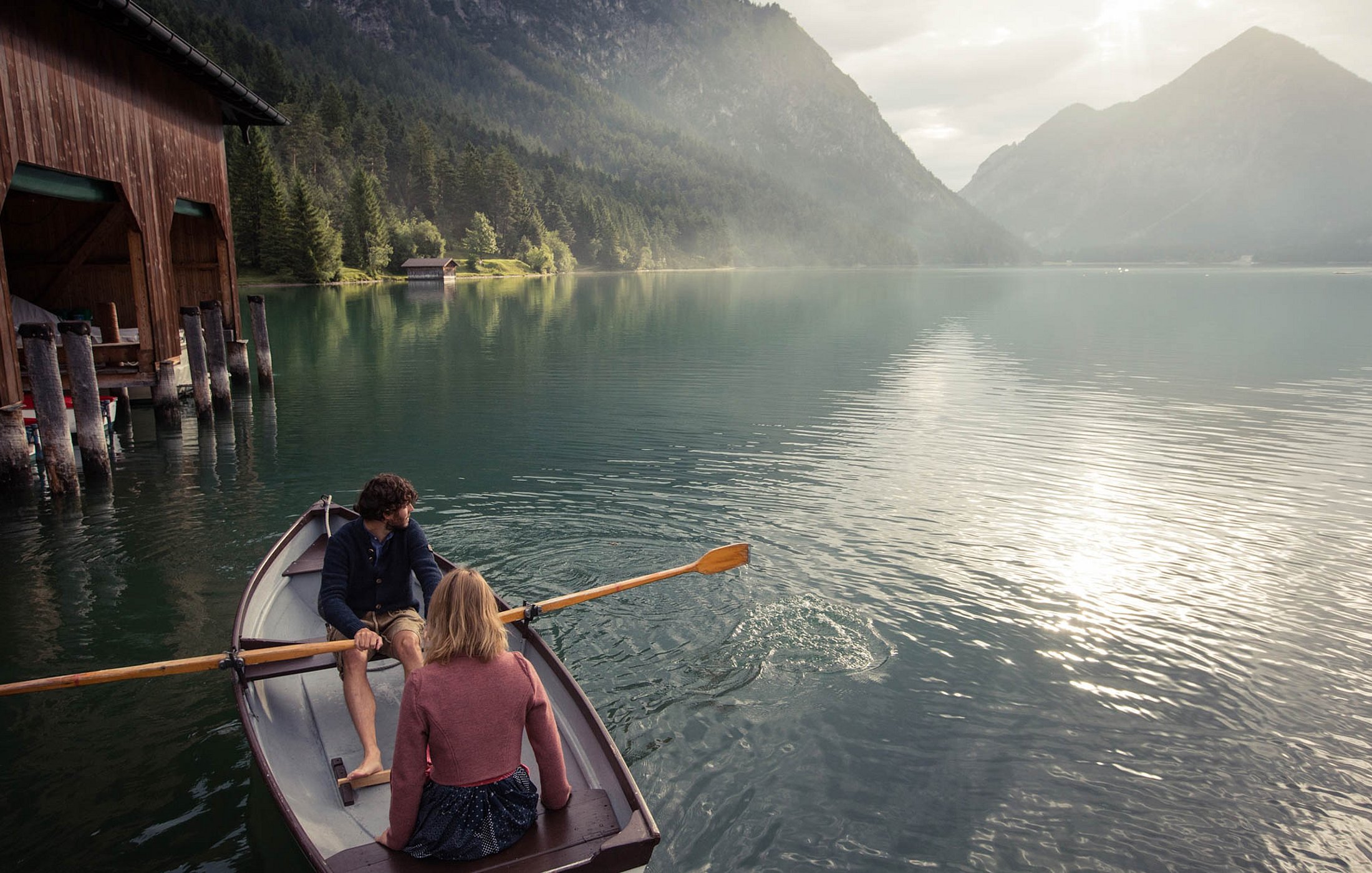 Couple in a rowboat near boathouse on Lake Heiterwang during a peaceful evening