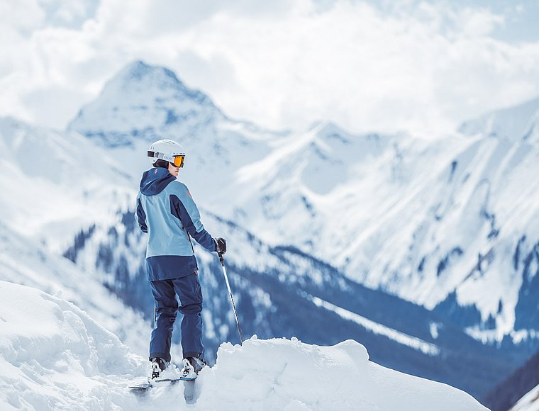 Skier overlooking snowy Alpine landscape with mountain peaks