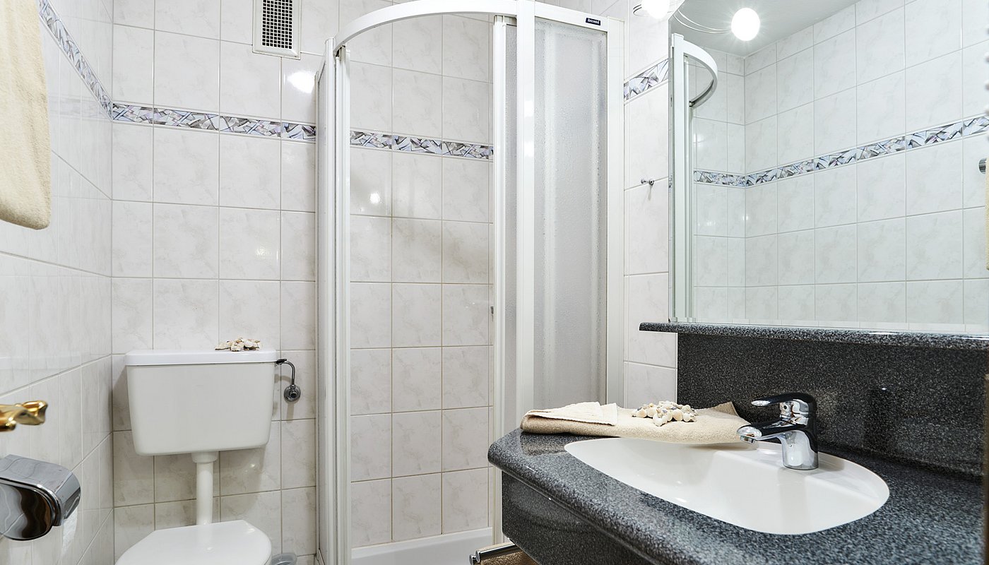 Bright bathroom with shower, sink, mirror and toilet in classic tiled design