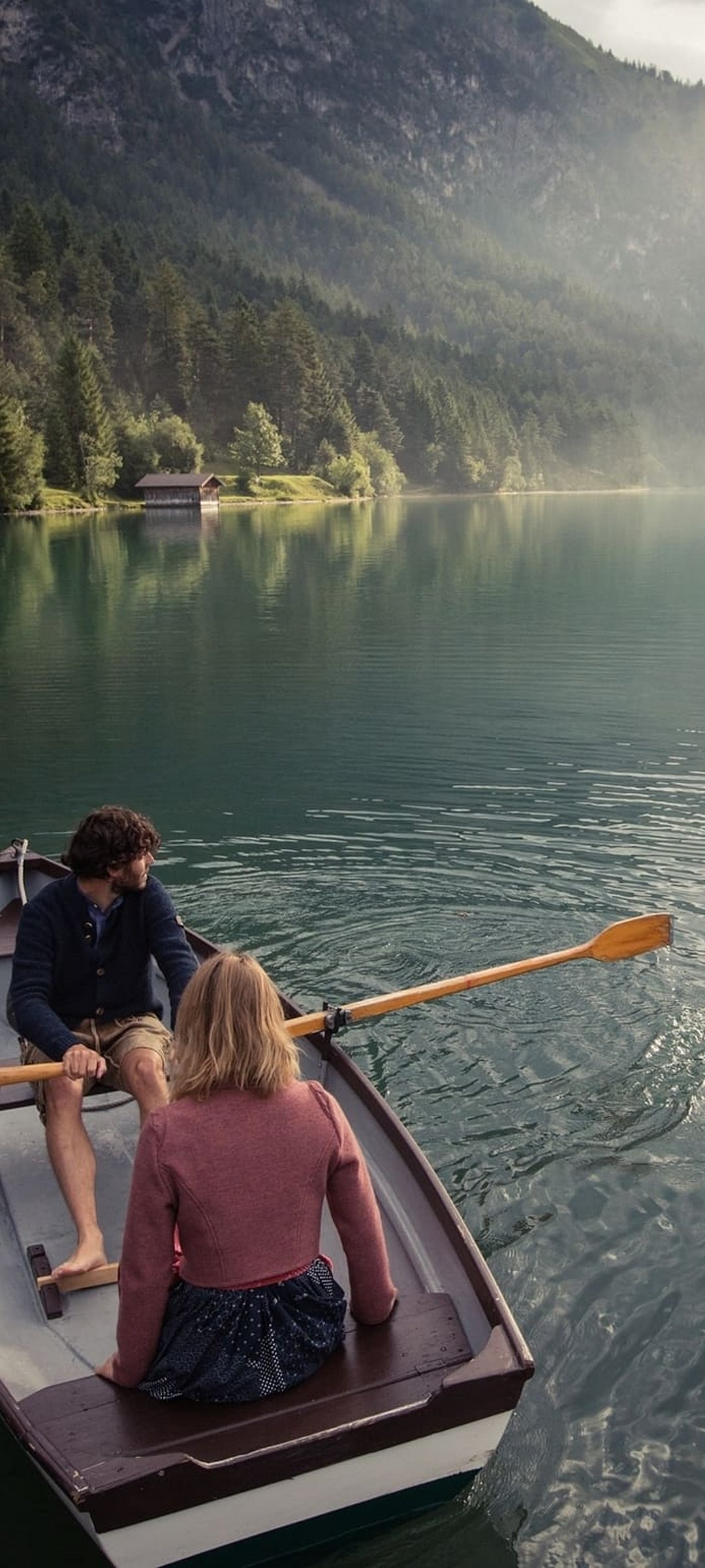 Couple in a rowboat near boathouse on Lake Heiterwang during a peaceful evening