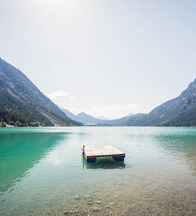 Wooden raft on Lake Heiterwang with mountain view in bright sunshine