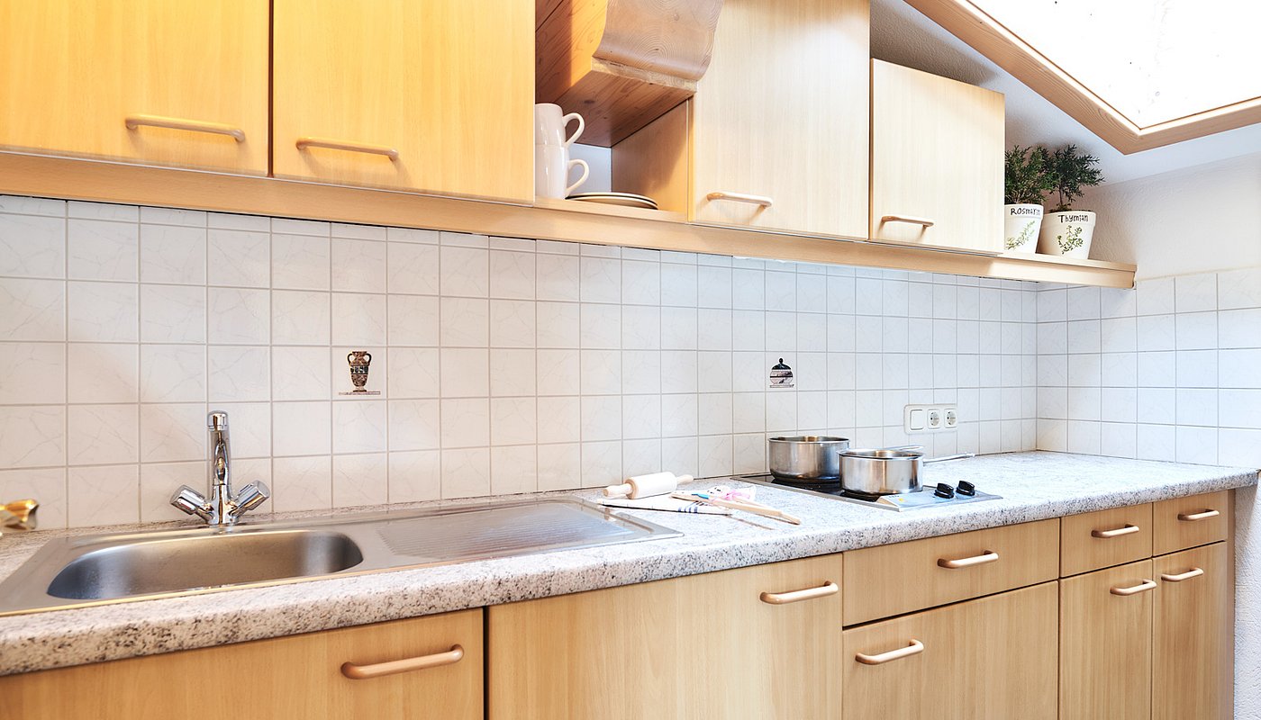 Bright holiday kitchen with stovetop, sink, pots and decor under skylight