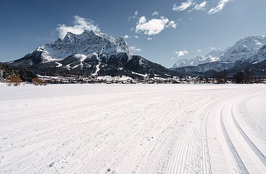 View of the Zugspitze with groomed winter trail in front of snow-covered village