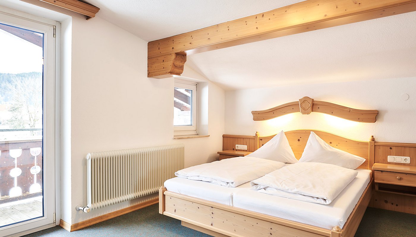 Cozy double room with wooden beds, nightstands and access to balcony with a scenic view