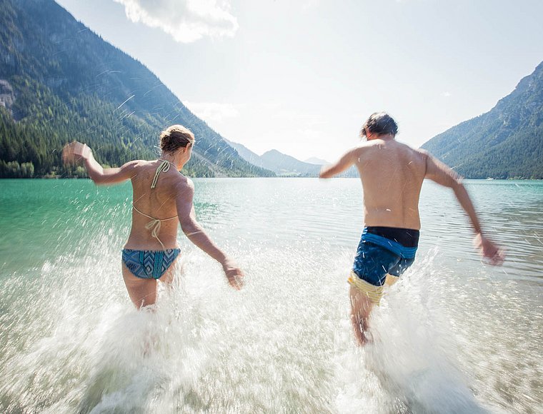 Two people laughing as they run into Lake Heiterwang on a summer day