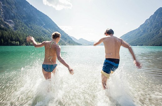 Two people laughing as they run into Lake Heiterwang on a summer day