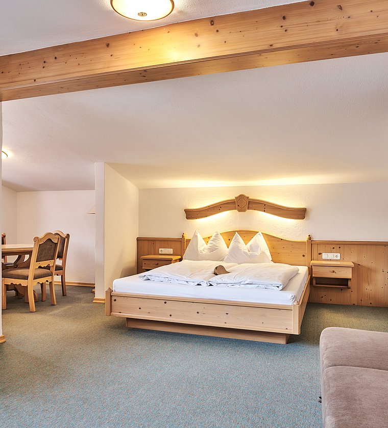 Cozy bedroom with wooden bed, seating area and visible wooden beam under the ceiling