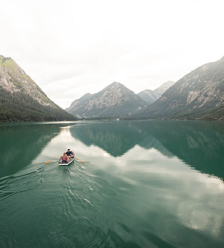 Couple rowing on calm Lake Heiterwang, surrounded by mountain scenery