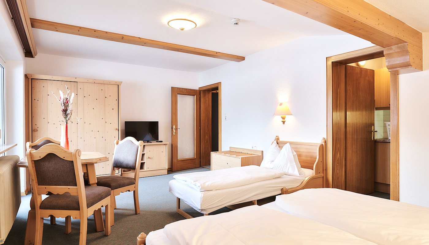 Living room view with TV, sitting area, dining table and door to the kitchen